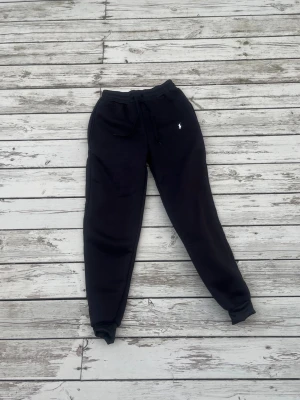 Svarta mjukisbyxor från Ralph Lauren - Säljer ett par svarta mjukisbyxor från Ralph Lauren med dragsko i midjan och resår vid bensluten. Byxorna har en liten vit logga broderad på vänster sida och är tillverkade i mjukt material som känns riktigt skönt mot huden.
