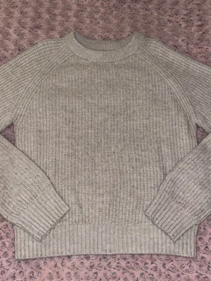 Beige stickad tröja med rund hals - Säljer en beige stickad tröja med rund halsringning och ribbade muddar vid ärmslutet. Har använt den max 2 gånger. Det var inget fel på den, den kom bara inte till användning :) Tröjan är mjuk, mysig och stretchig 🤍