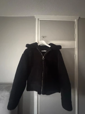 Svart teddyjacka från BikBok - Trendig svart teddyjacka från BikBok i storlek XS. Jackan har dragkedja framtill och är tillverkad i fluffigt teddy-material.
