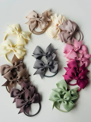 Färgglada hårsnoddar med rosetter - Säljer ett set med 20 stycken hårsnoddar dekorerade med stora ribbade rosetter i olika färger som beige, grå, rosa, vinröd, brun, grön och gul. Perfekta för att piffa till frisyren och ge en söt touch till din look. Elastiska band och rosetter i tyg.