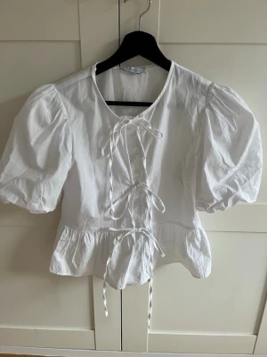Jättefin vit blus  - Söt vit blus med puffiga korta ärmar och knytning framtill. Rosetterna går att knyta upp själv! Jättefin och perfekt inför våren & sommaren. Passar perfekt till mig som är 166 cm. 💕Nypris- 599