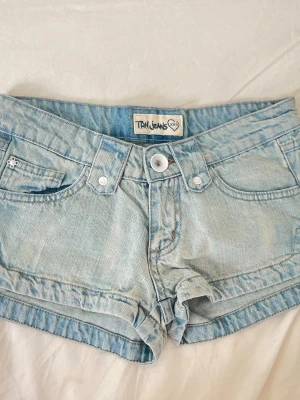 M2 Ljusblåa super lågmidjade lowrise vintage jeansshorts - Midja: ca 34 cm rakt över ! Gren ca 16-17 cm, 