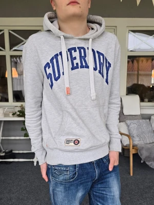 Superdry hoodie - Superdry hoodie i storlek Medium. Mycket bra skick förutom att trycket är lite slitet, men enligt mig är det lite coolt. Skriv om du undrar något.
