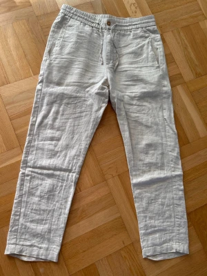 Beiga linnebyxor från Skagen clothing - Snygga beiga linnebyxor från Skagen clothing i storlek M. Byxorna har sidfickor fram och en bakficka. Nypris runt 1200kr. Materialet är 100% linne för en luftig känsla. Finns en liten fläck på högra benet som syns på bild 4 men är inget märkvärdigt. Vid frågor, mått eller fler bilder är det bara att höra av sig