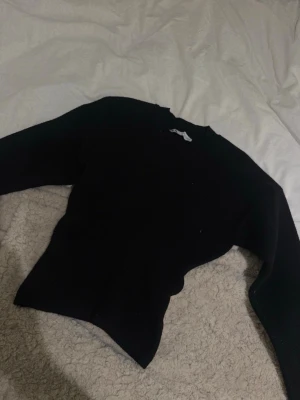 Svart stickad tröja - En svart stickad tröja med rund hals och lång ärm. Tröjan har en klassisk passform och är perfekt att styla med jeans eller kjol. Enkel och stilren design som funkar till många olika looks.