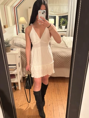 Vit kort klänning från Terranova - Säljer en vit kort klänning från Terranova i storlek M. Klänningen har v-ringad hals, tunna axelband som anpassas efter dig och volangdetaljer på kjolen. Dubbel kjol som gör att den inte blåser upp av en lätt bris eller är för genomskinlig. Perfekt för sommarens varma dagar och har en lätt och luftig känsla.