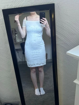 Vit spetsklänning offshoulder - Säljer en vit kortklänning med spetsdetaljer och offshoulder-design. Klänningen har figurnära passform och är fodrad under spetsen. Perfekt för dig som gillar en elegant och feminin stil. Strl M men passar absolut S!