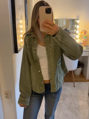 Olivgrön jeansjacka zara - Snygg olivgrön jeansjacka med klassisk krage och knäppning framtill. Två stora fickor på sidorna och detaljerade sömmar ger en cool och avslappnad look. Perfekt att slänga över en t-shirt för en trendig stil. Passar så bra nu till våren och sommaren!💖