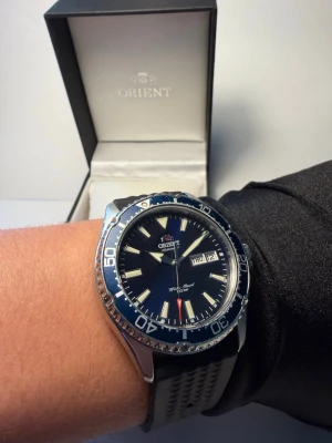 Orient Kamasu Automatic Diver 200m - Full set - Säljer min Orient Kamasu automatklocka i bra bruksskick. Mindre spår av användning förekommer. Se bilder för egen bedömning av skicket. En populär dykarklocka från japanska Orient med pålitligt automatiskt urverk. Klockan har en snygg mörkblå tavla med matchande vridring och tydliga luminova-index som lyser starkt i mörker. Den är vattentät till 200 m och passar både till vardag och mer sportig användning.    Ingår:  •Originalbox  •Manual / papper  •Original stållänk  •Extra länkbitar