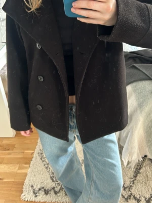 Svart kappa med knappar  - Snygg svart kappa från Gina med knappar. Passar perfekt till våren.