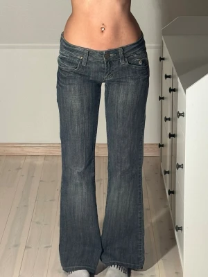 Low bootcut jeans  - Midjemått: 38cm. Innerbenslängd: 75cm. (Uppskattas vara en storlek 27.) Grå/blå färg. Sömnen i bensluten är uppsprättad, se bild. Kolla in min profil, följ för fler plagg🙌