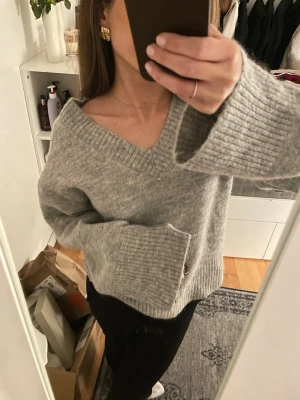 Ljusgrå stickad tröja med v-ringning  - Superfin ljusgrå stickad tröja med v-ringning och vida ärmar i oversized modell, går även att ha som off shoulder (sista bilden). Knappt använd!