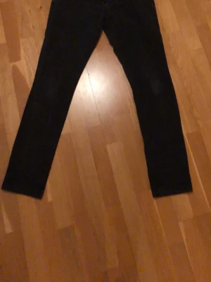 Svarta leggings med smal passform - Säljer ett par svarta slim fit jeans med raka ben och klassisk femficksmodell. Jeansen har en enkel och stilren look, perfekta till sneakers eller boots. Materialet ser ut att vara en bomullsblandning med lite stretch för extra komfort.