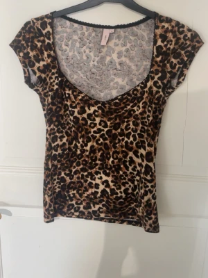 Leopardmönstrad topp från Nelly - Snygg leopardmönstrad topp från Nelly med korta ärmar och djup rundringning. Tunn och stretchig i materialet. Aldrig använt men har tagit av prislappen
