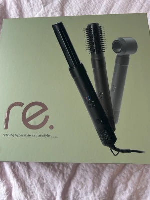 re. hyperstyle air hairstyler - Multifunktionell svart hårstyler från re. med tre utbytbara munstycken: rundborste, fönmunstycke och stylingstav. Perfekt för att skapa olika frisyrer med luft och värme. Modern design med digitala knappar och sladd.