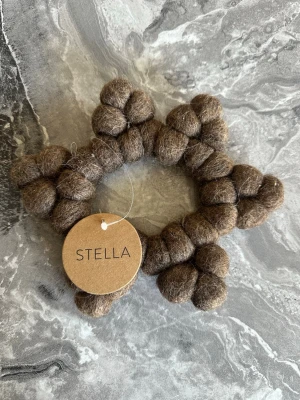 Brun grytunderlägg från Stella - Ett grytunderlägg i brun ull från Stella, formad som en stjärna. Tillverkad av små bollar av filtad ull som är sammanfogade till en unik och lekfull design.  Ny. Pris 80kr
