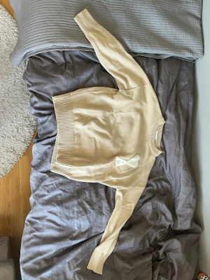 Ami Paris Tröja - Snygg beige stickad tröja från Ami Paris med ribbade muddar och bred ribbad nederkant. Storlek är M men ganska stor i bredden. Tröjan är andvänd endast en gång. 