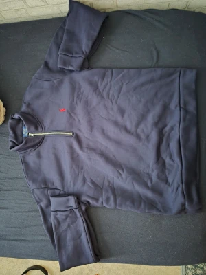 Mörkblå halvzip hoodie från Polo Ralph Lauren och det är xl men passar på L - Snygg mörkblå hoodie från Polo Ralph Lauren med halv dragkedja och klassisk röd broderad logga på bröstet. Tillverkad i mjukt bomullsmaterial och har ribbade muddar vid ärmslut och nederkant. Perfekt för en avslappnad och stilren look.