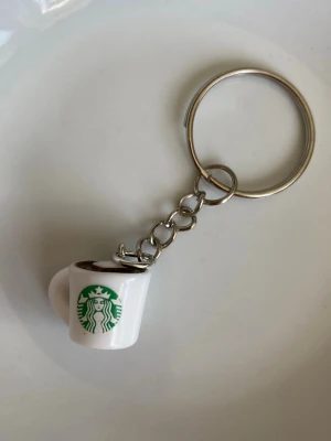 Starbucks nyckelring kaffekopp - Säljer en söt nyckelring från Starbucks med en miniatyrmugg i vitt och grönt. 