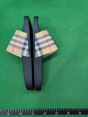 Burberry tofflor - (OBSSS NI FÅR EN LÄNK DÄR NI KÖPER PRODUKTEN NI FÅR EJ TOFFLORNA) Snygga tofflor från Burberry med klassiskt beige, svart och rött rutmönster på remmen. Sulan är svart och tillverkad i gummi, medan ovandelen har textil med det ikoniska Burberry-mönstret. Perfekta för en trendig och avslappnad look.