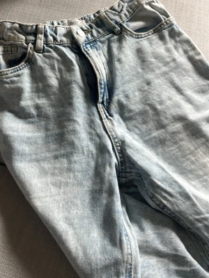Ljusblå mom jeans från Lindex - Säljer ett par ljusblå mom jeans från Lindex med medium hög midja och klassisk femficksdesign. Jeansen har en avslappnad passform och är tillverkade i bomullsdenim. Perfekta för en chill och trendig look.