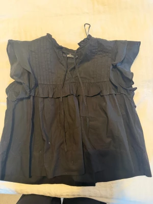 Svart volangblus  - Svart oanvänd blus från ginatricot. Skit snygg för någon utekväll eller bara vanlig vardag. Är lite kort vid magen men inte så att det syns, det beror mest på storleken. XS men passar S också.