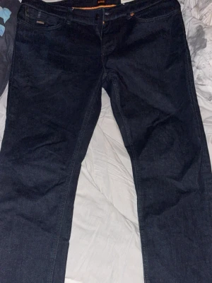 Mörkblå slim fit jeans boss  - Snygga mörkblå slim fit jeans från boss. Klassisk femficksmodell med dragkedja och knapp. Jeansen har en stilren look och är tillverkade i denim med en lätt stretch för extra komfort.