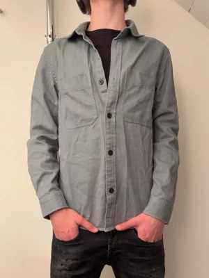 Olivgrön Overshirt  - Tjabba! Säljer nu denna HM overshirten i storlek XSmen passar som sen stor S! Den är i ett nytt sick, använd nån få gång, inga defekter! Om ni har några tankar eller funderingar så är det bara att hör av sig!😄