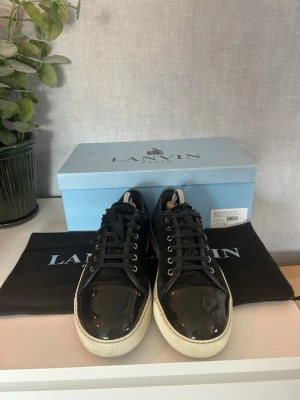 Lanvins - Stilrena svarta sneakers från Lanvin med snygg glansig tå i skinn och ovandel i mocka. Klassisk låg modell med vita sulor och svarta snören. Perfekta för dig som vill ha en clean och lyxig look med exklusiv känsla. Allt og, uk7 motsvarar 41/42
