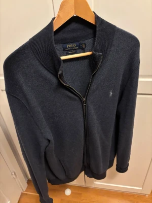 Mörkblå ziptröja Ralph Lauren - Mörkblå ziptröja från Ralph Lauren i storlek M, i pima cotton. Priset är förhandlingsbart så det är bara att buda. Köpt hos Vinofino