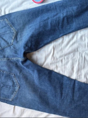 Tiger of Sweden  - Säljer ett par blå jeans med raka ben och klassisk femficksdesign. Jeansen har normalhög midja och är gjorda i denim. Perfekta för en avslappnad och stilren look. Typ helt nya 