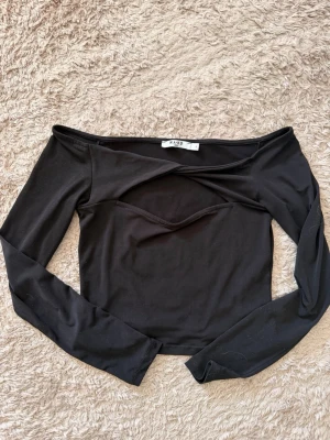 Svart offshoulder topp från NA-KD - Trendig svart offshoulder topp från NA-KD med lång ärm och snygg cut-out detalj framtill