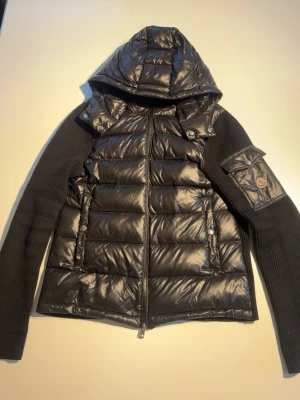 Moncler Tricot Cardigan svart – strl M - Säljer min Moncler tricot cardigan i svart, storlek M.  Klassisk modell med quiltad dunfront, huva och stickade ärmar. Använd men i fint skick. Dragkedjan fungerar som den ska.  Storlek: M Färg: svart  Kan skicka fler bilder eller mått vid intresse.