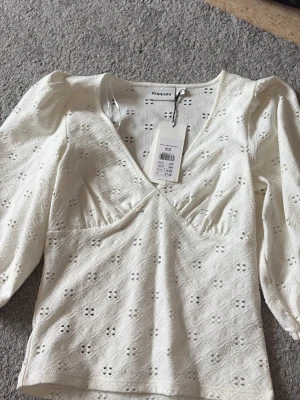 Vit blus med broderade detaljer Kappahl - Superfin vit blus från Kappahl helt ny  med v-ringning och broderade blommor. Blusen har puffiga trekvartsärmar och är gjord i bomull med spetsdetaljer. Perfekt till SOMMAREN !! Helt ny 