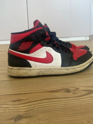 Air Jordan 1 Mid Svart/Röd/Vit - Snygga Air Jordan 1 Mids. Passar till allt.  Det syns att dom är använda men inga stora skador eller fel. Hör av er vid frågor 😃