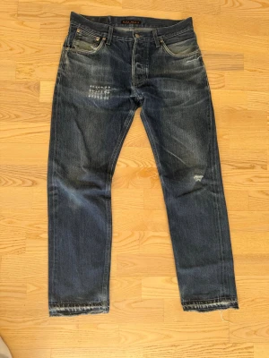 Nudie Jeans Dry Greytone Selvage - Säljer ett par selvedge jeans från Nudie jeans. Färg: Dry Greytone Selvage. Modell: Steady Eddie. Väl använda med slitningar och en lagning med sashiko. Storlek 30/30eller W30/L30. 