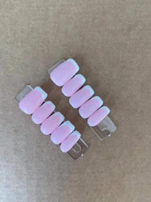 Franska press-on naglar rosa/vit - Snygga press-on naglar i klassisk fransk design med ljusrosa bas och vit tipp. Naglarna har en oval form och ger en fräsch och stilren look. Perfekta för dig som vill fixa naglarna snabbt och enkelt hemma.