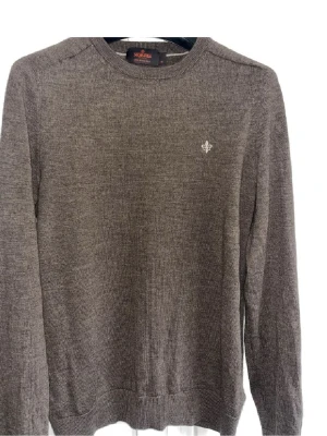 Brun stickad tröja från Morris - Snygg brun stickad tröja från Morris med rund halsringning och diskret broderad logga på bröstet. Tillverkad i mjukt material som passar perfekt till lager på lager. Klassisk och stilren design med ribbade muddar vid ärmslut och nederkant.