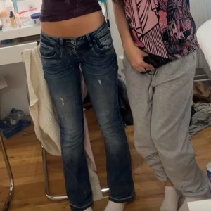 Mörkblå bootcut jeans från LTB - Snygga mörkblå jeans från LTB med bootcut passform och låg midja. Jeansen har slitna detaljer framtill, klassiska fem fickor och en cool tvätt som ger en avslappnad vibe. Perfekta för dig som gillar en lite retro look och vill ha jeans med lite extra attityd.