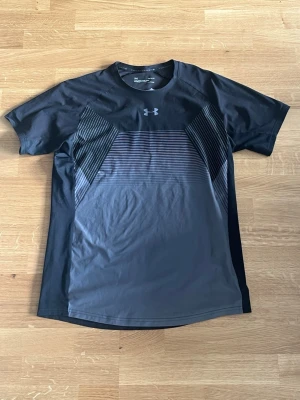 Under Armour svart tränings-tshirt - Säljer en svart och mörkgrå tränings-tshirt från Under Armour, modell Threadborne HeatGear. Hör av er vid frågor!