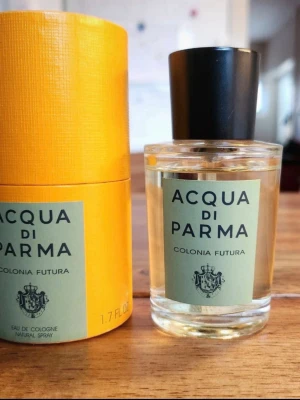 Acqua di Parma Colonia Futura EdC - OANVÄND - Fräsch Eau de Cologne från Acqua di Parma, Colonia Futura. Kommer i en stilren, rund glasflaska med svart kork och ljusgrön etikett. Förpackningen är gul och cylinderformad, vilket ger en lyxig känsla. Perfekt för dig som gillar klassiska och eleganta dofter.