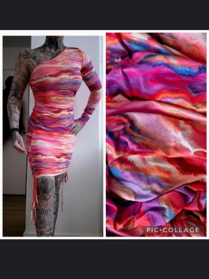 Oneshoulder kortklänning i färgstarkt mönster - Säljer en oneshoulder kortklänning med färgstarkt abstrakt mönster i rosa, lila, orange och rött. Klänningen har lång ärm på ena sidan och snörningsdetaljer i sidorna för en tight passform. Perfekt för dig som vill sticka ut!