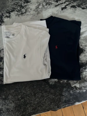 2-pack t-shirts från Polo Ralph Lauren - Två klassiska t-shirts från Polo Ralph Lauren, en vit och en svart. Båda har rund halsringning och den ikoniska broderade loggan på bröstet. Perfekta basplagg i mjuk bomull med normal passform. Båda för 250 en för 150!!