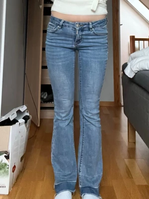 Low waist bootcut jeans - Säljer ett par ljusblå bootcut jeans med låg midja med slitningar längst ner som ska vara där. Stl xxs eller 35 cm tvärs över och 75,5 cm i innerbenslängd men det är stretchiga i midjan