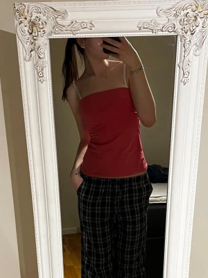 Röd/rosa tub topp - Snygg röd/rosa tub topp. Toppen har en enkel, figurnära passform och är perfekt för varma dagar. Tillverkad i mjukt material som känns bekvämt mot huden. Enkel att styla med olika outfits. Den övre delen viker man under. I storlek S men skulle passa M också.