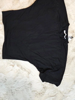 Svart basic t-shirt från 157 ny m.lapp storl.L - En enkel svart t-shirt från 157 med klassisk rund hals och korta ärmar. Tillverkad i mjuk bomull som känns skön mot huden. Perfekt till jeans eller shorts för en clean och avslappnad stil.