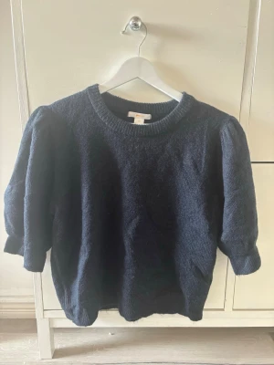 Mörkblå stickad tröja med puffärm från Gina Tricot - Säljer en mörkblå stickad tröja med rund hals och puffade ärmar från Gina Tricot. Tröjan har kortare ärmar och ribbstickade kanter. Perfekt för dig som gillar en enkel men trendig look. Jag har vanligtvis xs i storlek och den passar toppen på mig. Den är endast använd en gång och är som ny💕