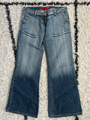 Jeans 💙 - Säljer ett par blå lågmidjade raka jeans med snygga slitningar och tvättade detaljer. Jeansen har framfickor med sned öppning och breda benslut för en retro vibe. Storlek W31/L30 💙  
