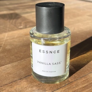 ESSNCE Vanilla Sass' Eau de Parfum - ESSNCE Vanilla Sass' Eau de Parfum i en rund glasflaska med svart lock. Doften har en tydlig vaniljkaraktär och flaskan har en stilren vit etikett. Perfekt för dig som gillar söta och mjuka dofter med en modern touch. Nästan hela kvar, parfymen går ungefär till övre kanten av ettiketten.