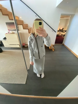 Ljusgrå zip hoodie med huva - Säljer en ljusgrå hoodie med dragkedja och huva. Hoodien har snörning i huvan, två fickor framtill och ribbade muddar vid ärmar och nederkant. Perfekt för en avslappnad och chill stil. Materialet känns mjukt och bekvämt, troligen bomullsblandning.